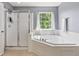 Bright bathroom with a large soaking tub, separate shower, and natural light from the window at 15936 Symphony Blvd, Noblesville, IN 46060