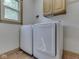 This laundry room features modern washer and dryer sets, upper cabinets, and a window at 3601 Lakeshore Ct, Greenwood, IN 46143