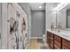 Well-lit bathroom with a floral shower curtain, double vanity, and ceramic tile flooring at 4809 Ozark Ln, Indianapolis, IN 46239