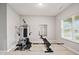 Home gym with full body workout machine, bench press, window, and light carpet at 4844 Morenci Ct, New Palestine, IN 46163
