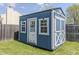 Charming blue storage shed with a white trim, windows and a door, nestled in a backyard with a grassy lawn at 6602 Cobden Ct, Indianapolis, IN 46254