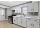 Modern kitchen features white cabinets, stainless steel appliances, a gas range, and laminate floors at 733 S Holmes Ave, Indianapolis, IN 46221