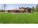 Expansive backyard features well-manicured lawn, brick home with wood deck, and outdoor patio, a great space for outdoor living at 7901 Oaklandon Rd, Indianapolis, IN 46236