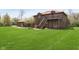 Spacious backyard boasts lush green lawn, complemented by a brick home with a wooden deck and stairs, ideal for relaxation and outdoor activities at 7901 Oaklandon Rd, Indianapolis, IN 46236