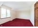 Bright bedroom featuring neutral walls, a window, and plush red carpeting for a cozy atmosphere at 7901 Oaklandon Rd, Indianapolis, IN 46236