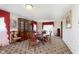 Traditional dining room featuring a large round table, floral carpet, and window with red curtains at 7901 Oaklandon Rd, Indianapolis, IN 46236