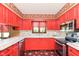 Kitchen with red cabinets, white countertops, black appliances, and rooster-themed wallpaper at 7901 Oaklandon Rd, Indianapolis, IN 46236