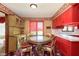 Eat-in kitchen with small glass table, chairs, red cabinets, and rooster-themed wallpaper at 7901 Oaklandon Rd, Indianapolis, IN 46236