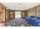 Living room features wood-paneled walls, patterned carpet, and a blue velvet sofa at 7901 Oaklandon Rd, Indianapolis, IN 46236