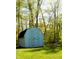 Outdoor shed with double doors amidst a lush green lawn and wooded backdrop at 9067 Old Haggard Rd, Morgantown, IN 46160