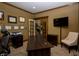 A spacious office with a large dark wood desk, neutral chair, a flat screen TV and multiple awards on the wall at 10138 Backstretch Row, Fishers, IN 46040