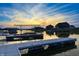 A long dock with boat slips reflects the colors of a vibrant sunset over the tranquil lake at 10590 Geist View Dr, Fishers, IN 46055
