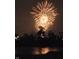 A brilliant fireworks display illuminates the night sky over the trees and a reflective body of water at 10590 Geist View Dr, Fishers, IN 46055