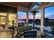 Covered outdoor patio with a view of the lake at dusk and comfortable seating at 10590 Geist View Dr, Fishers, IN 46055