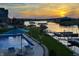 A scenic pool area with an umbrella offers shade while overlooking the lake and dock at sunset at 10590 Geist View Dr, Fishers, IN 46055