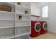 Well-organized laundry room with red washer and dryer and ample shelving units for storage at 10919 Running Tide Ct, Indianapolis, IN 46236