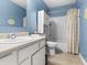 Well-lit bathroom featuring a vanity, toilet, shower with curtain, and white cabinetry at 11327 Cuyahoga Dr, Indianapolis, IN 46235