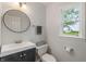 Neutral powder room offers a round mirror, dark vanity, and a window with a view at 1285 S 1100 E, Zionsville, IN 46077