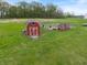 View of a red barn, storage sheds and fencing, situated on a manicured lawn at 1285 S 1100 E, Zionsville, IN 46077