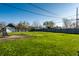 View of a large, grassy backyard with a gray fence and a detached garage at 1509 S Spencer Ave, Indianapolis, IN 46203