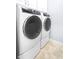 Updated laundry room features white front load washer and dryer with grey accents and upper cabinets at 16201 Haywood St, Fishers, IN 46037