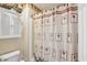 Neutral bathroom features a shower with palm tree shower curtain, and a cabinet with storage above the toilet at 19248 Searay Dr, Noblesville, IN 46060