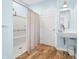 Modern bathroom with a walk-in shower, wood floors, a wall-mounted sink, and a white door at 2001 E Ely Ct, Martinsville, IN 46151