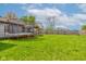 Large backyard with a wood privacy fence, trampoline, covered deck, and green grass at 2125 Jason Dr, Lebanon, IN 46052