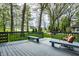 A gray wood deck with benches and chairs surrounded by mature trees provides space for outdoor relaxation at 225 Yorkshire E Blvd, Indianapolis, IN 46229