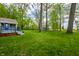 A green backyard with mature trees and a shed provide ample space for recreation and relaxation at 225 Yorkshire E Blvd, Indianapolis, IN 46229