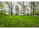 Lush, green backyard with storage shed and mature trees offers a serene outdoor space at 225 Yorkshire E Blvd, Indianapolis, IN 46229