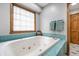 Bathroom featuring a jacuzzi tub with teal tiling and a wood framed window at 225 Yorkshire E Blvd, Indianapolis, IN 46229