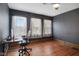 Bedroom featuring dark walls, hardwood floors, three windows, and a desk at 25 N Wayburn St, Indianapolis, IN 46229