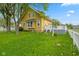 Charming yellow two-story home with a green lawn and mature trees under a blue sky at 25 N Wayburn St, Indianapolis, IN 46229