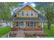Charming yellow two-story home featuring a welcoming front porch with brick accents and a classic white picket fence at 25 N Wayburn St, Indianapolis, IN 46229
