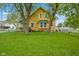 Beautiful two-story yellow home with a spacious front yard and mature shade trees at 25 N Wayburn St, Indianapolis, IN 46229