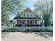 Charming two-story home with yellow siding, white trim, and a welcoming front porch and white picket fence at 25 N Wayburn St, Indianapolis, IN 46229