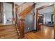 Classic wooden staircase with detailed trim, hardwood floors, and glimpses of the living room and kitchen at 25 N Wayburn St, Indianapolis, IN 46229