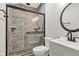 Modern bathroom featuring pebble accents in shower, sliding glass door, updated vanity and round mirror at 257 N Tacoma Ave, Indianapolis, IN 46201