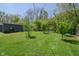 The backyard boasts lush green space with mature trees and a storage shed, great for gardening and outdoor activities at 2658 S Rybolt Ave, Indianapolis, IN 46241