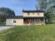Charming two-story home features a cozy front porch, a red door, and well-maintained landscaping at 3008 N Michigan Rd, Shelbyville, IN 46176