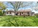 An expansive backyard showcases a home with a red door, green lawn, and a convenient storage shed at 3027 Ash Way, Lapel, IN 46051