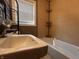 Well-lit bathroom featuring a sink, a bathtub with tiled walls, and a window at 3541 Orchard Ave, Indianapolis, IN 46218