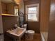 Bathroom featuring a sink, a toilet, and a bathtub with tiled walls and a window at 3541 Orchard Ave, Indianapolis, IN 46218