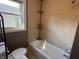 Bathroom featuring a toilet, a bathtub with tiled walls, and a window at 3541 Orchard Ave, Indianapolis, IN 46218