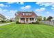 Charming two-story home with red roof, white porch, and a beautifully landscaped green lawn under a blue sky at 429 E Main St, Whiteland, IN 46184