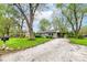 Charming single-story home with a gravel driveway, lush green lawn, and mature trees providing ample shade at 5141 Annette St, Indianapolis, IN 46208