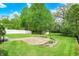 Landscaped backyard with stone patio, trees, storage shed, and white fence at 5341 Armstrong Dr, Indianapolis, IN 46237