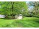 Lush backyard features a storage shed, mature trees, a firepit, and well-maintained lawn at 5341 Armstrong Dr, Indianapolis, IN 46237