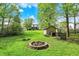 Large backyard with fire pit, shed, trees, and a house in the background at 5341 Armstrong Dr, Indianapolis, IN 46237